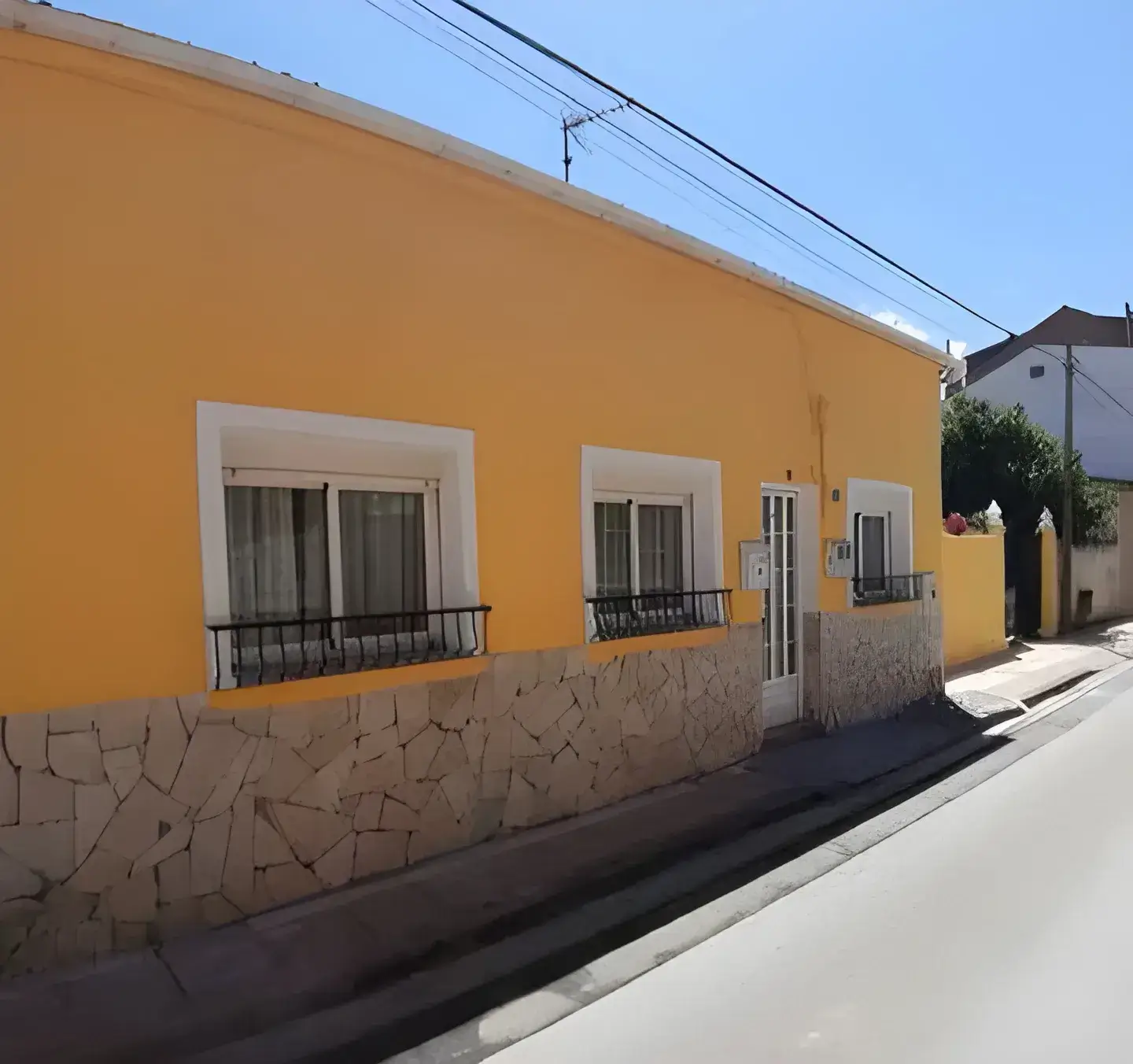 Los Pintores en Sevilla Fachada de casa tradicional pintada en color amarillo con zócalo de piedra
